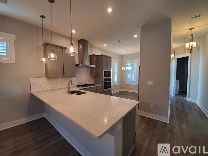 A modern kitchen with a large island and pendant lights.