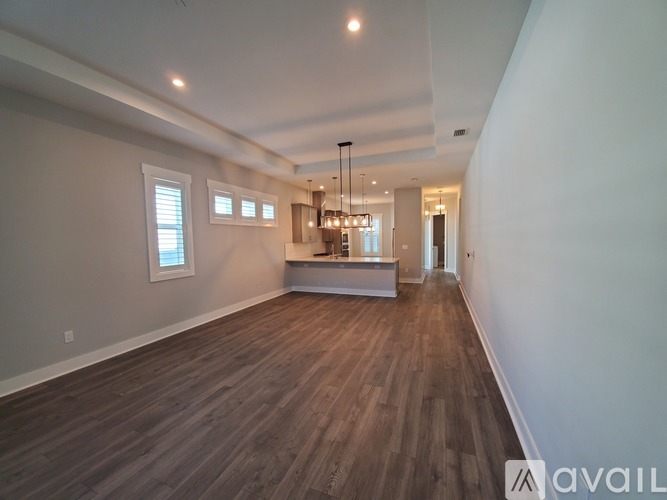 A spacious room with wooden flooring and a bar area in the middle.