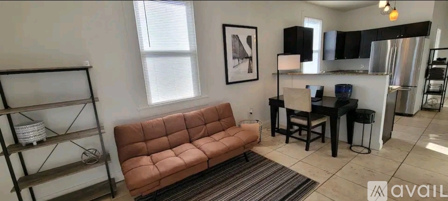 A living room with a brown couch and a black dining table.