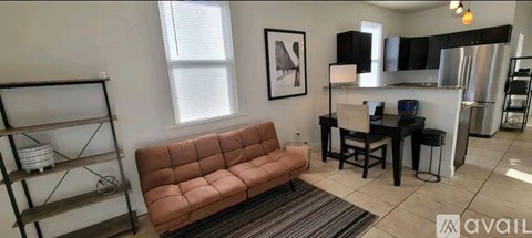 A living room with a brown couch and a black dining table.