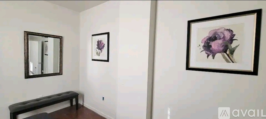 A hallway with a bench and two framed pictures on the wall.