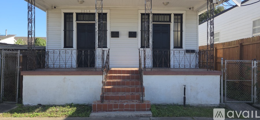 A white house with a black door and a brick staircase leading to the front door.
