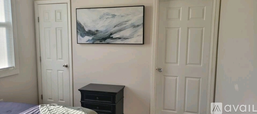 A bedroom with a bed, a nightstand, and a painting on the wall.