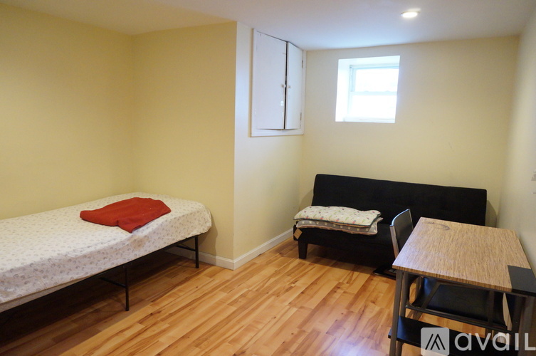 A bedroom with a bed, a chair, a table, and a window.