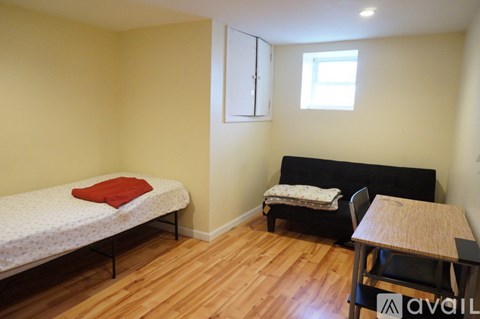 A bedroom with a bed, a chair, a table, and a window.