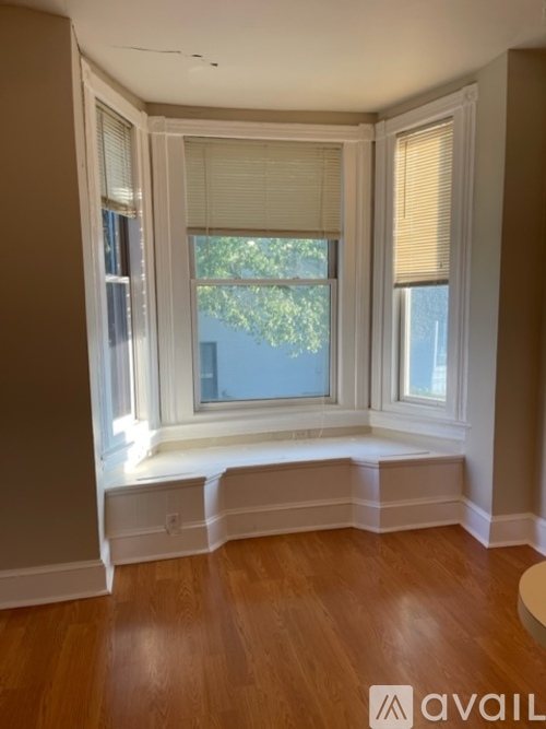 A room with a window seat and wooden floors.