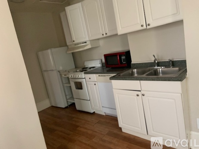 A kitchen with white cabinets and a red microwave.