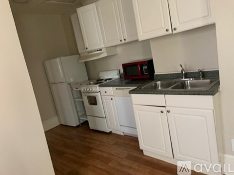 A kitchen with white cabinets and a red microwave.