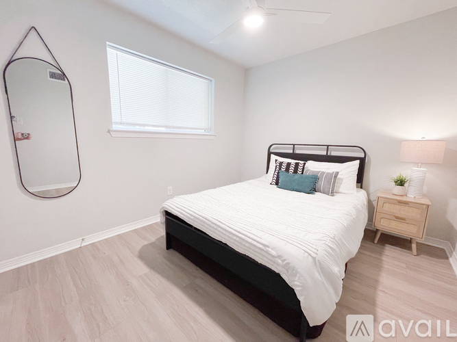 A bedroom with a large bed, a mirror, and a small nightstand.