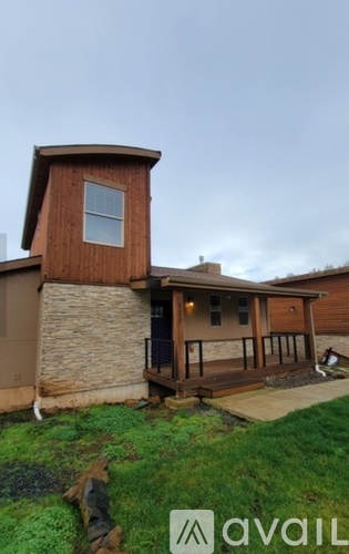 A house with a brown wooden exterior and a stone wall.