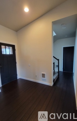 A room with dark wood floors and white walls.