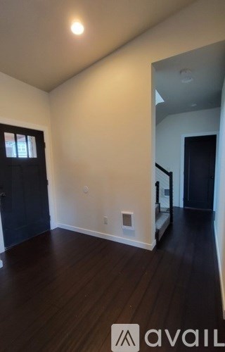 A room with dark wood floors and white walls.