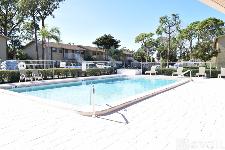 A pool surrounded by a white fence and trees.
