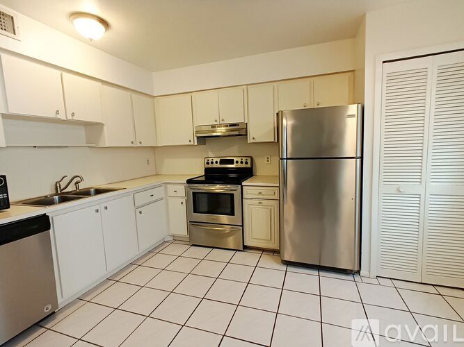 A kitchen with white cabinets and a stainless steel refrigerator.