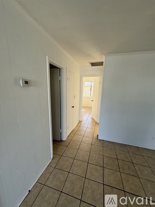 A hallway with tiled flooring and white walls.
