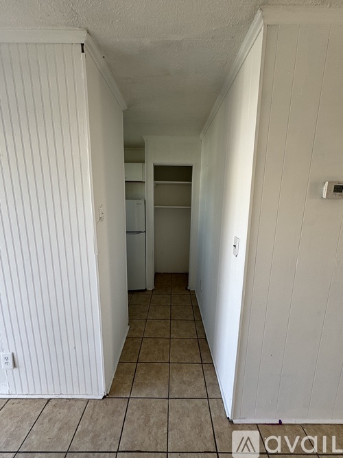 A long white hallway with a door on the right.