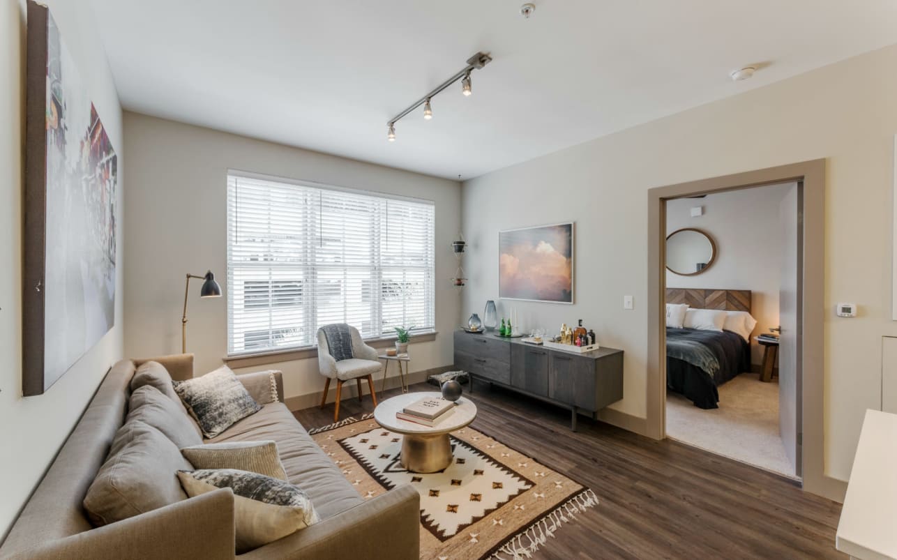 A living room with a brown couch and a rug.