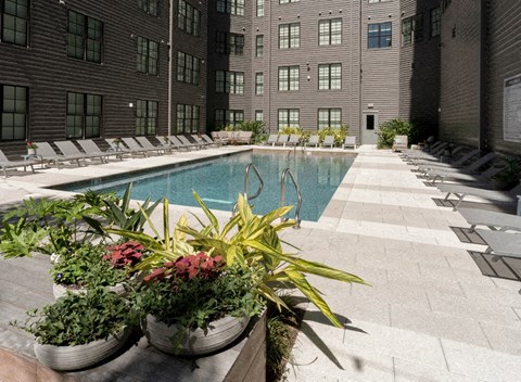the pool is surrounded by potted plants in front of a building