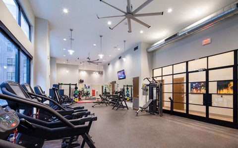 a gym with weights and chairs and a ceiling fan