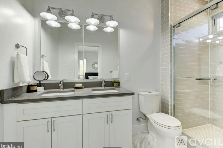A bathroom with a white toilet, a sink with a mirror above it, and a glass shower stall.