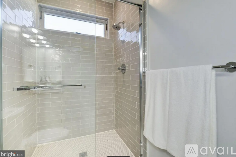 A bathroom with a glass shower stall and a white towel hanging on the door.