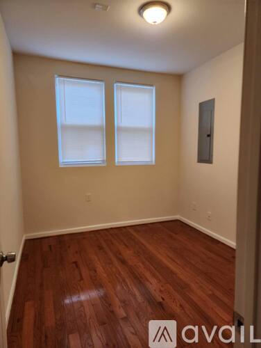 A room with wooden floors and two windows.