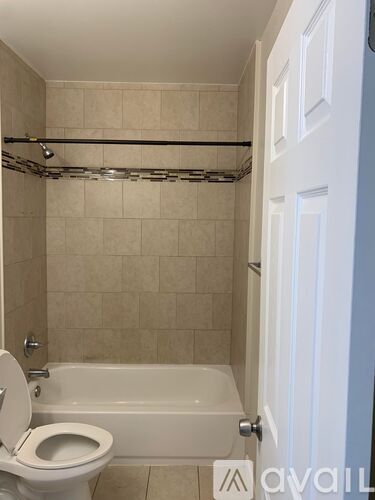 A bathroom with a toilet, tub, and towel rack.