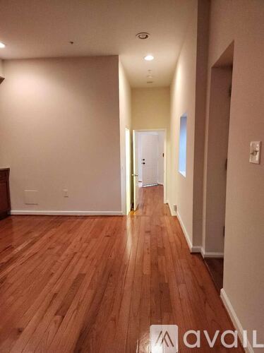A hallway with wooden floors and white walls.