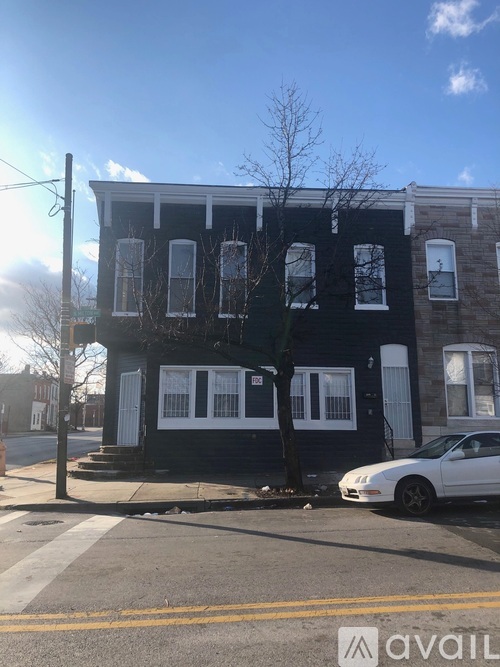 A white car is parked in front of a black building.