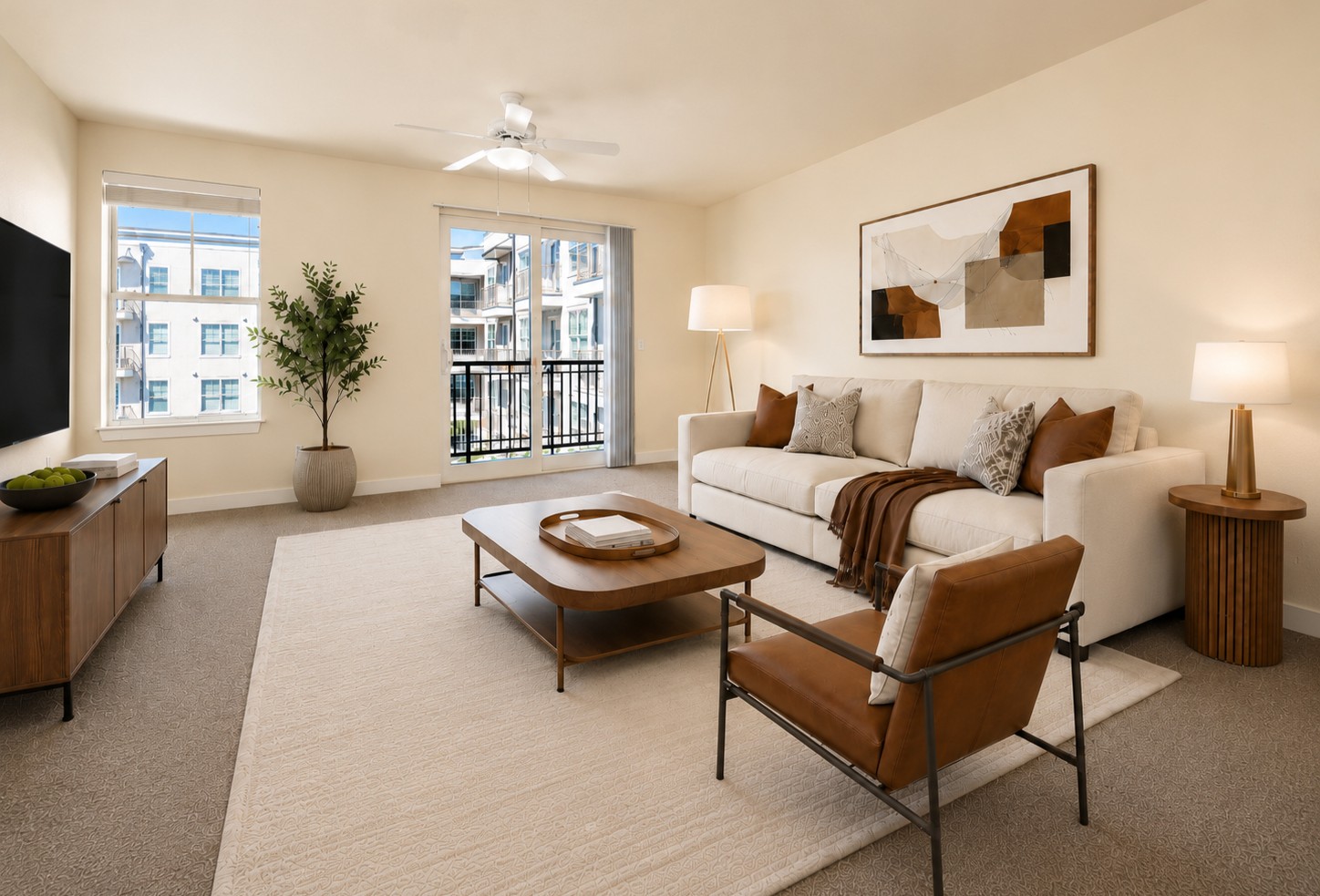A living room with a white couch, a brown chair, and a large window.
