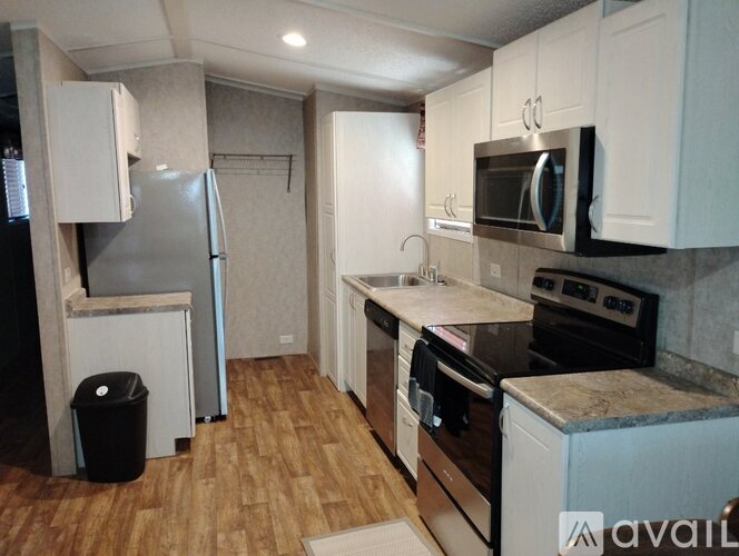A kitchen with a refrigerator, microwave, oven, and sink.