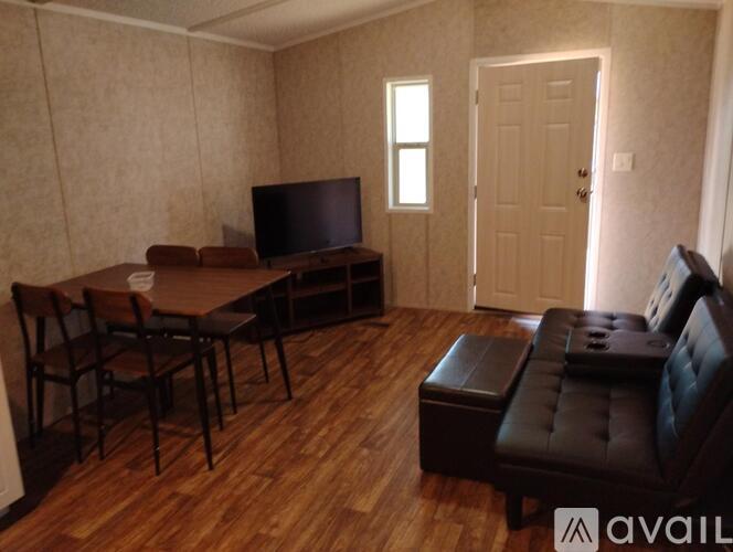 A living room with a television, two chairs, and a table.