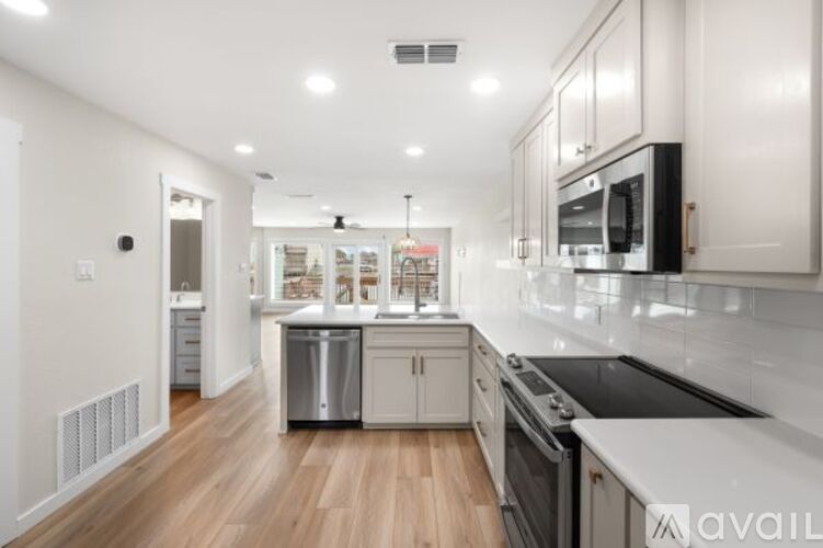 A modern kitchen with wooden floors and stainless steel appliances.