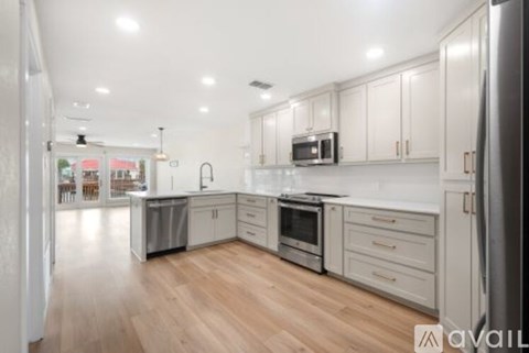 A kitchen with white cabinets and a wooden floor.