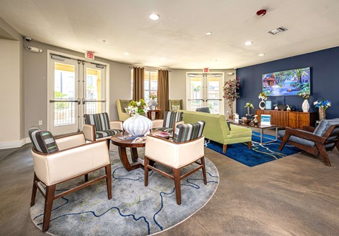 A living room with a large rug and a TV on the wall.