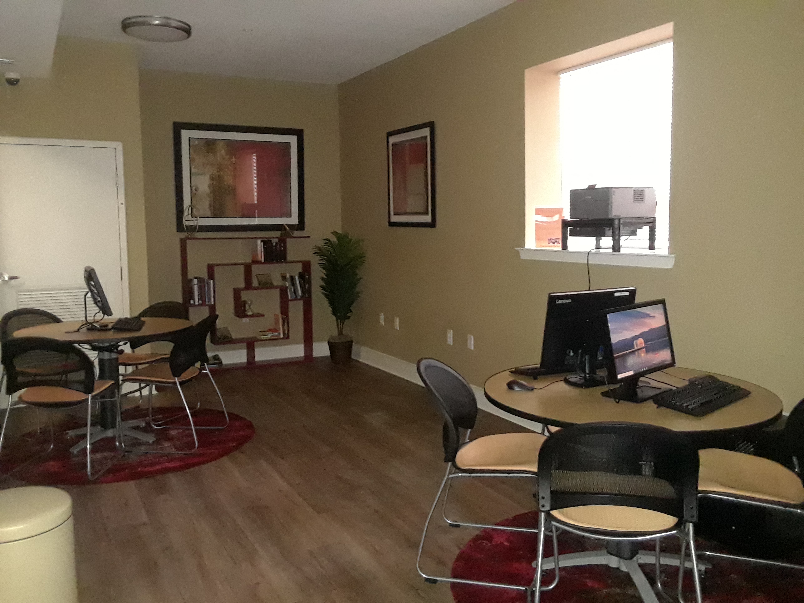 a room with a desk with a computer and chairs