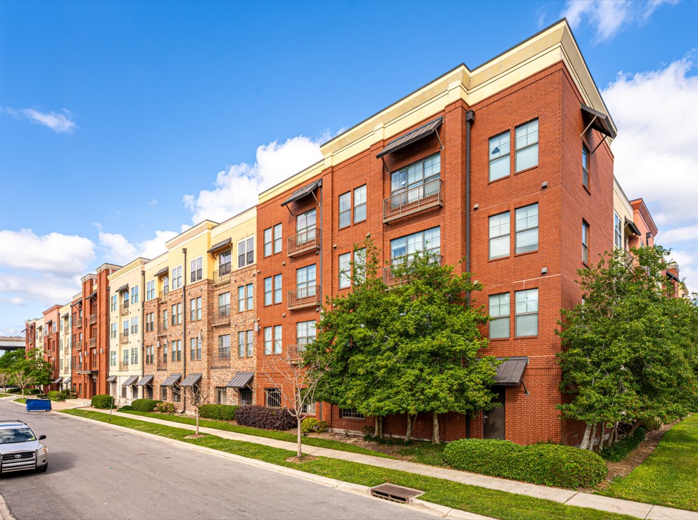 A row of red brick apartment buildings with trees in front.