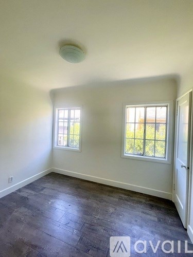 A room with a grey floor and two windows.
