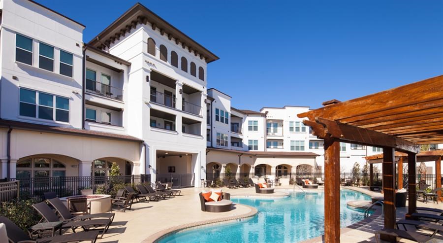 a swimming pool with patio furniture in front of buildings