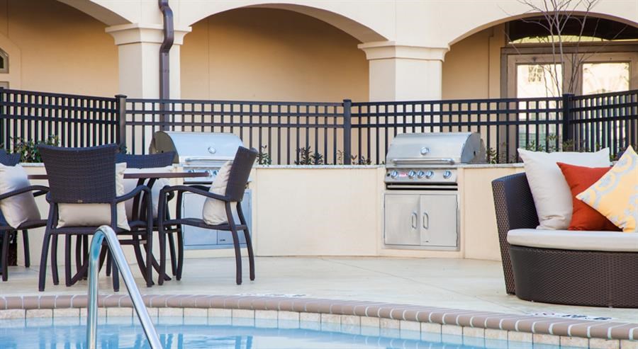 a swimming pool with tables and chairs and a barbecue grill