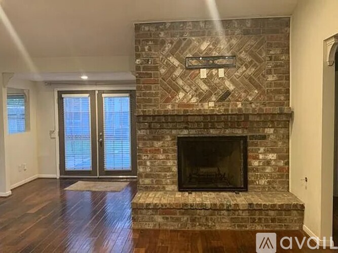 A brick fireplace in a room with wooden floors and a glass door.