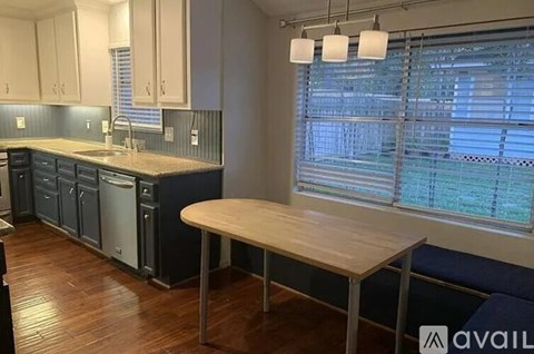 A kitchen with a table and a window with blinds.