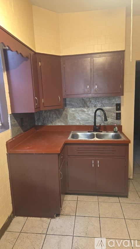A kitchen with brown cabinets and a stone backsplash.