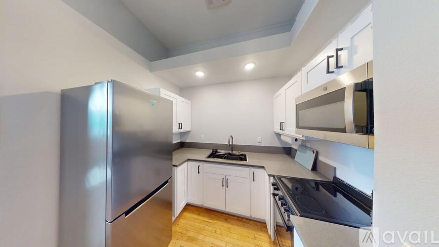 A modern kitchen with a refrigerator, microwave, and oven.