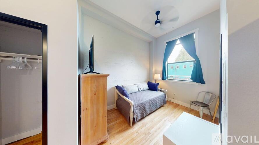 A bedroom with a bed, chair, and a window with a view.