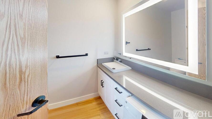 A bathroom with a sink, mirror, and wooden door.