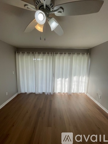 A room with a ceiling fan and wooden flooring.