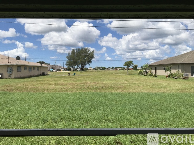 A grassy field with a few buildings in the distance.