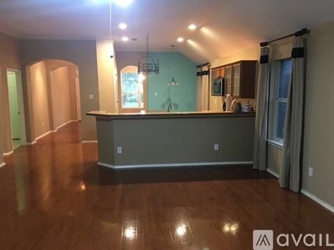 A room with wooden floors and a bar area.