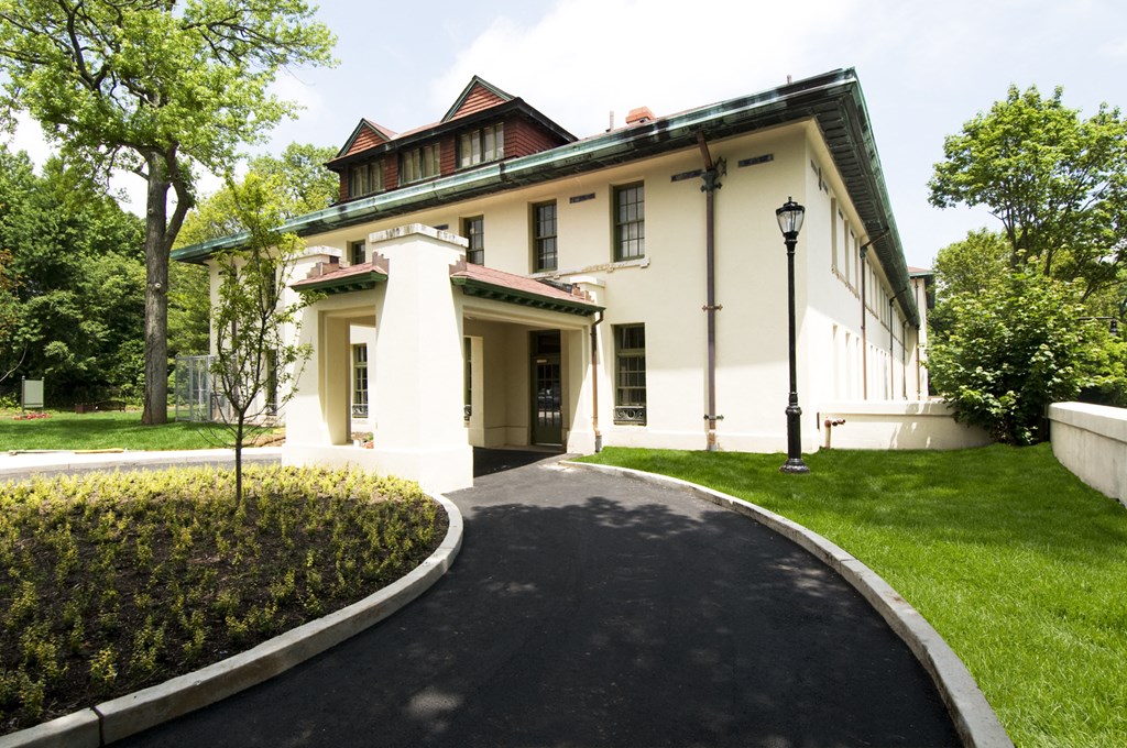 a large white house with a driveway and lawn and trees